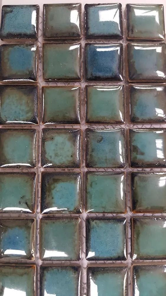 Grid of small square teal and brown tiles with reflective surfaces, shown close up.