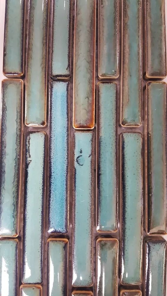 Vertical mosaic of narrow turquoise glass tiles with copper-colored grout lines