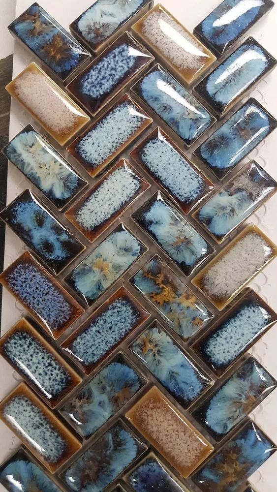 Diagonal pattern of blue, tan, and brown glass mosaic tiles on a white background
