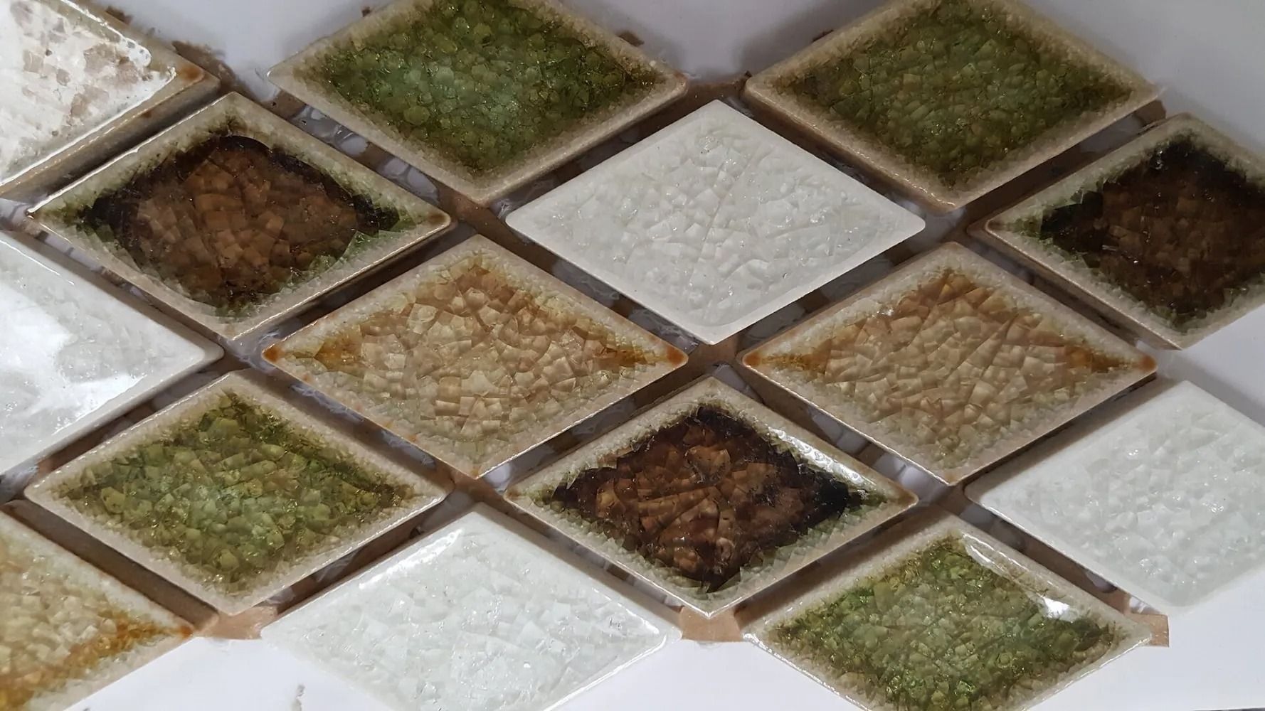 Diamond-pattern mosaic tiles in white, brown, and green tones on a wall or backsplash