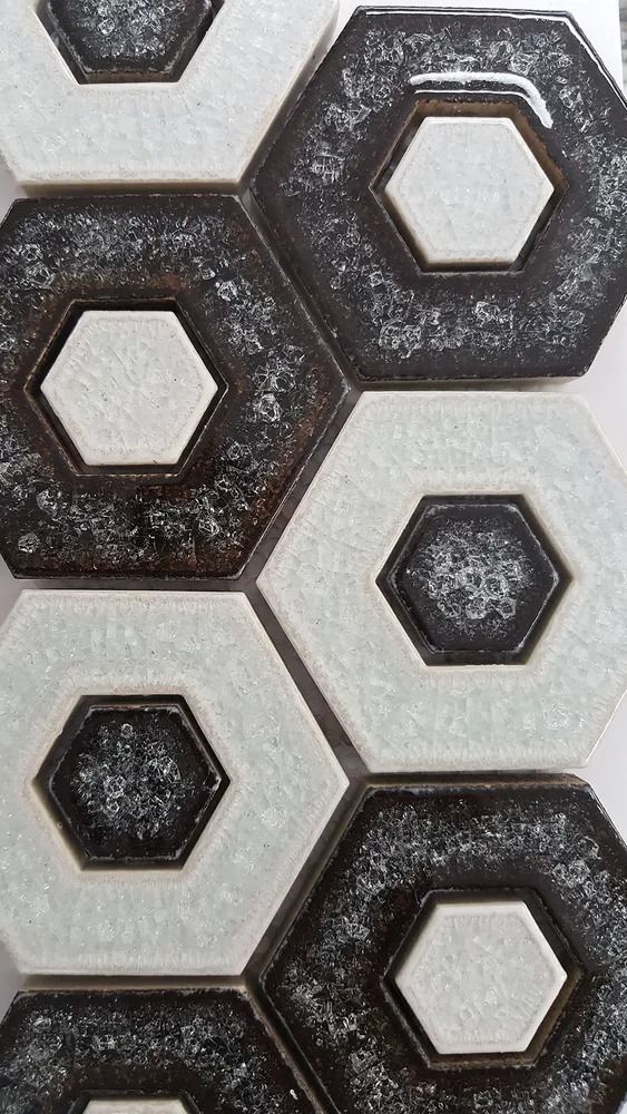 Hexagonal tile pattern in gray and dark brown, with raised geometric shapes on a textured surface