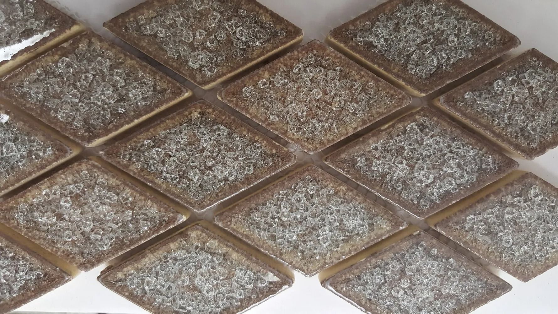 Close-up of a white diamond-patterned tiled surface with brown borders and speckled gray centers