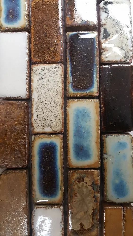 Vertical mosaic of glossy rectangular tiles in brown, white, blue, and black tones