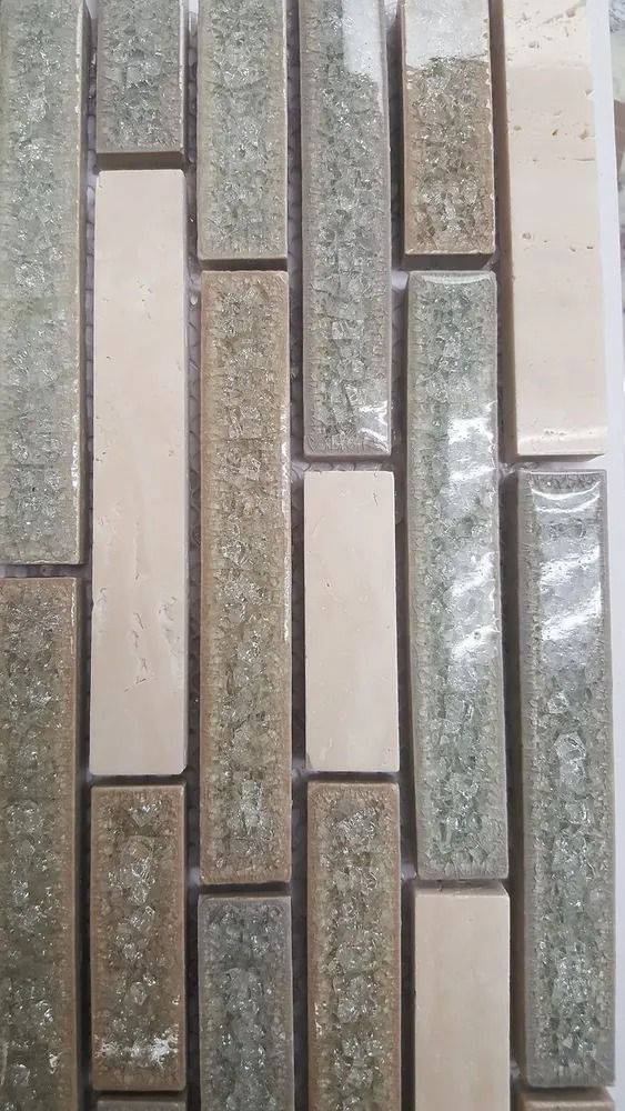 Vertical mosaic of beige, gray, and speckled stone tiles in a narrow rectangular pattern