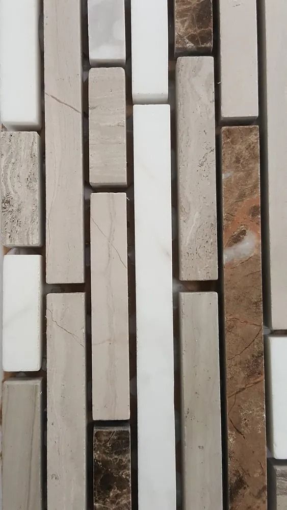 Vertical mosaic of narrow white, gray, and brown stone tiles with thin dark grout lines