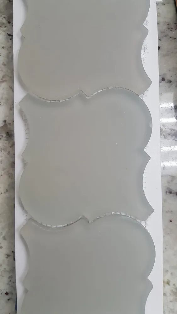 Three blank white ornamental labels arranged vertically on a gray surface