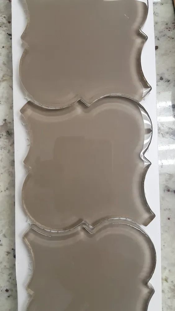 Three stacked beige scalloped decorative tiles or coasters on a light surface.