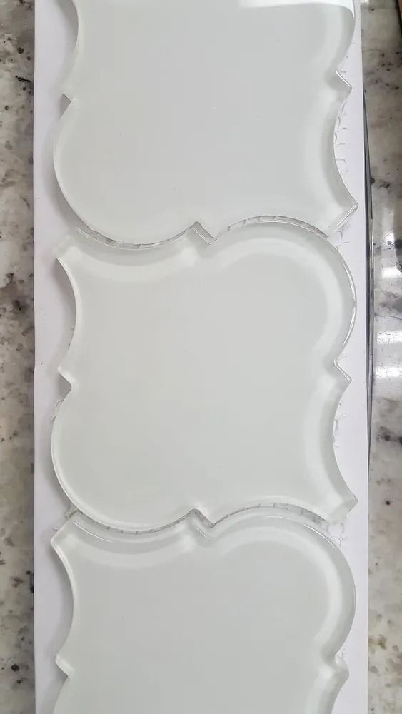 White decorative mold with three scalloped rectangular sections on a gray speckled surface