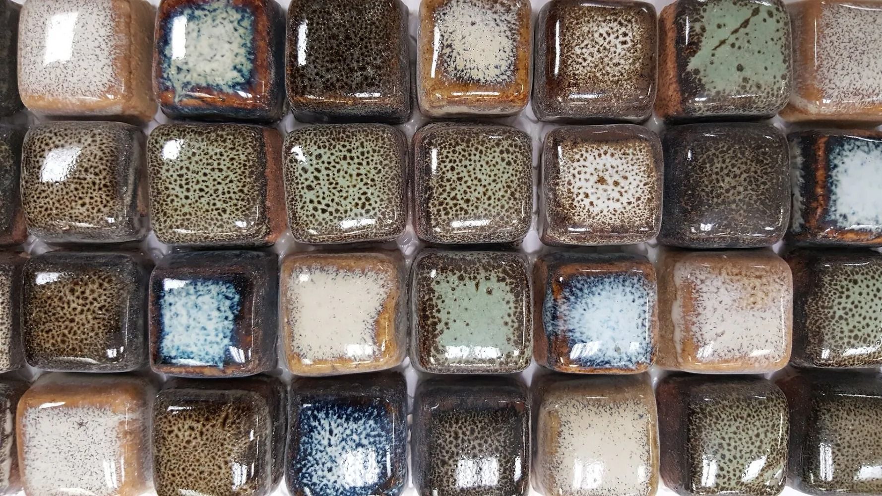 Close-up of square ice cubes or chocolate pieces, brown and white with frosty highlights, arranged in rows