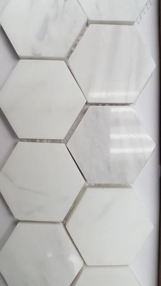 White hexagonal wall tiles with a subtle marble pattern and glossy reflections