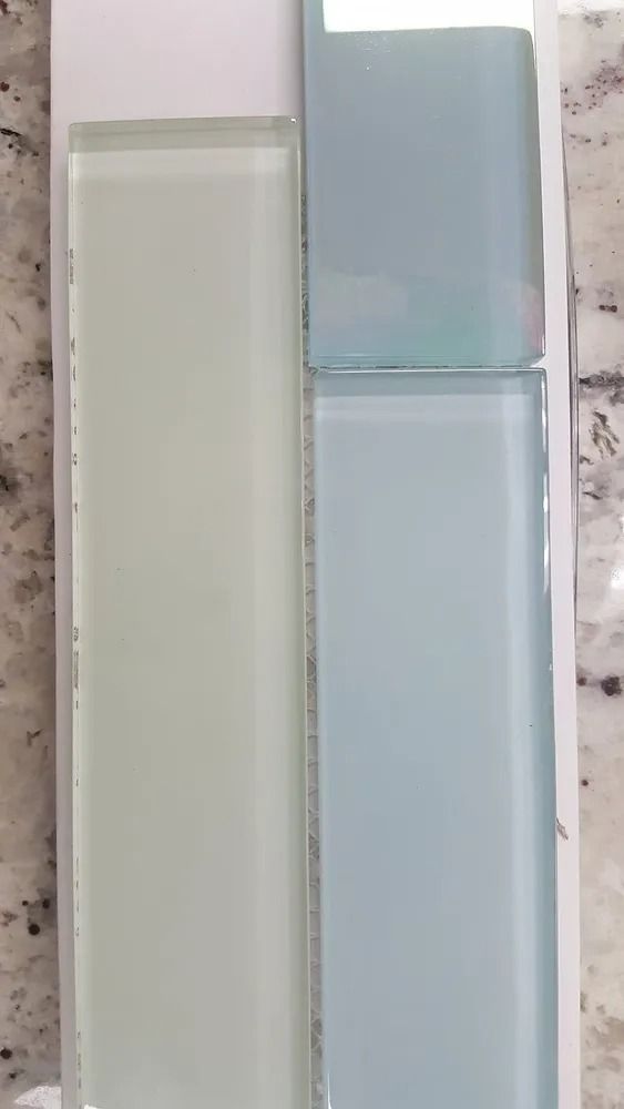Two rectangular glass tiles, one white and one pale blue, displayed side by side.
