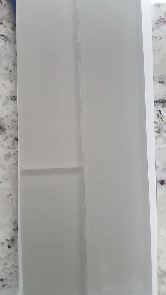 Close-up of a white wall with a vertical seam and a small ledge near the bottom left.