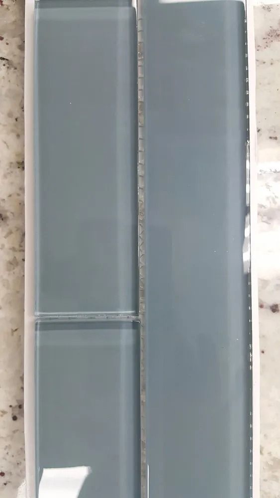 Two tall gray glass panels with metal frames, viewed vertically against a light wall.