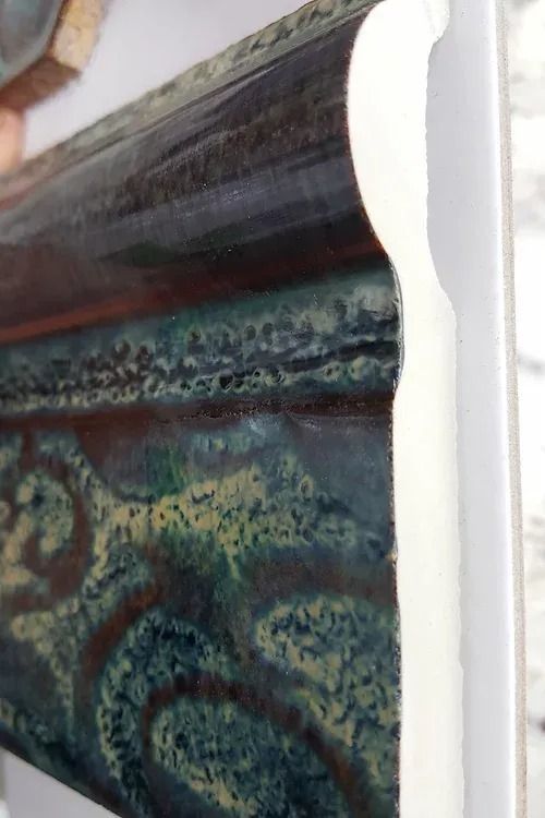 Close-up of a colorful marbled glass panel with dark, blue-green, and rust tones.