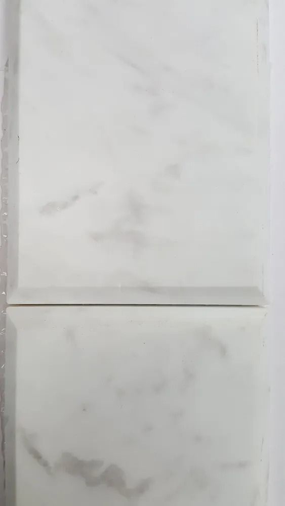 White marble-look tiled wall with a horizontal seam and gray veining.