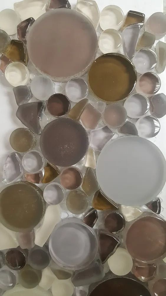 Abstract mosaic of translucent round glass pebbles in beige, white, gray, and brown tones