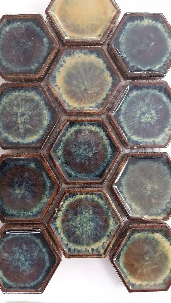 Nine hexagonal ceramic tiles in muted blue, green, and brown tones on a white background.