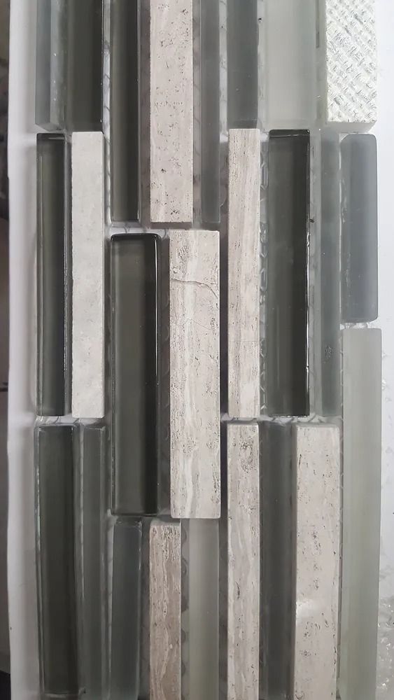 Vertical mosaic of gray, black, and white glass tiles with a textured light background