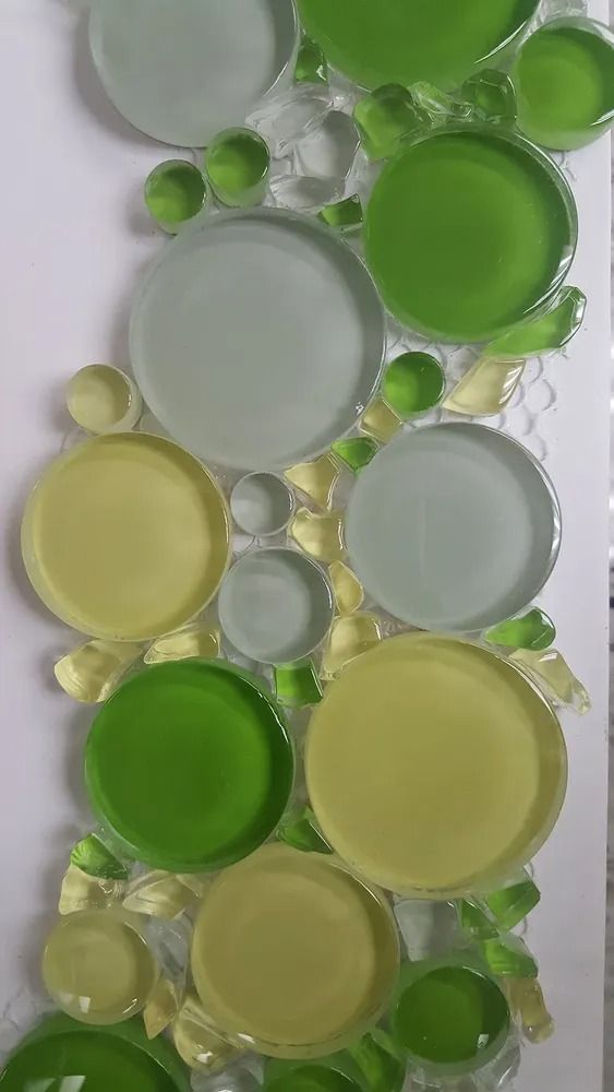 Abstract arrangement of translucent green, yellow, and frosted circular glass discs on a white background