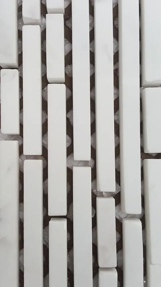 White vertical rectangular tiles arranged in a staggered mosaic pattern with gray grout lines
