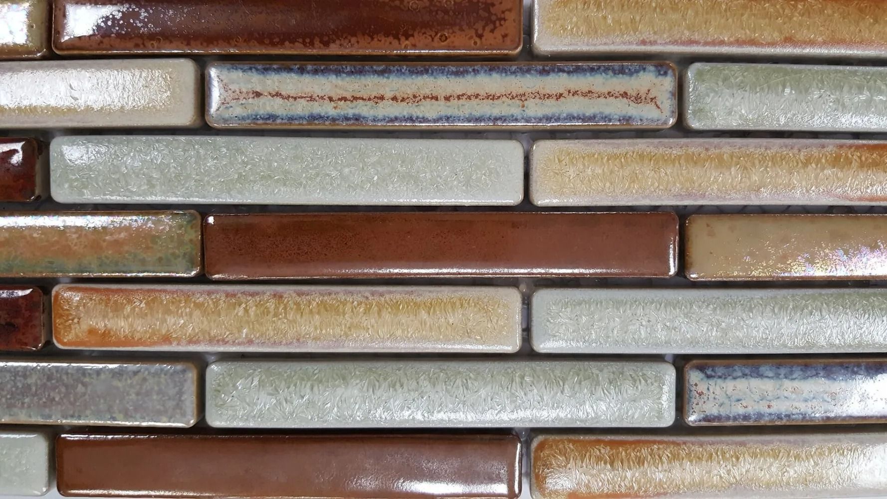 Close-up of a brick wall with alternating brown, gray, and tan bricks