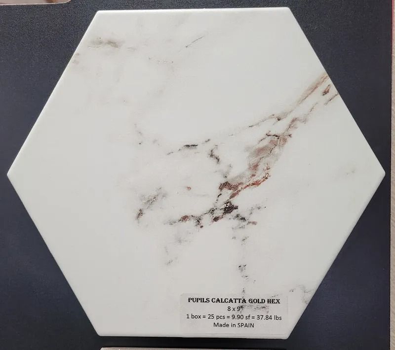 Hexagonal white marble-look tile with subtle gray and brown veining on a dark background.
