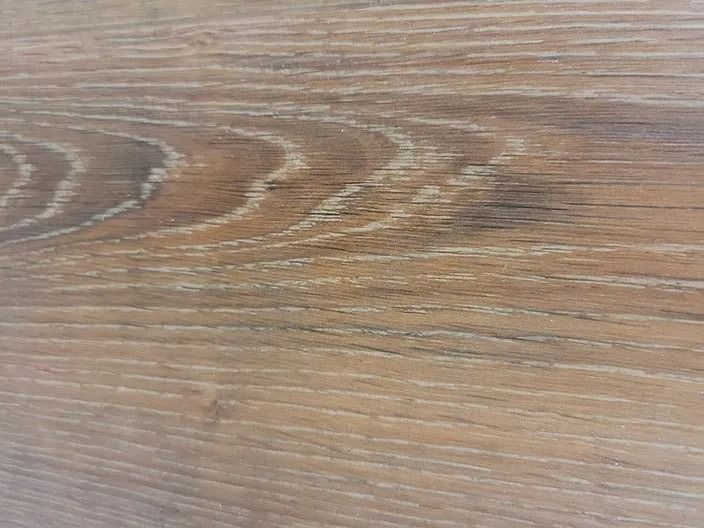 Close-up of a light brown wood-grain surface with visible knots and streaks