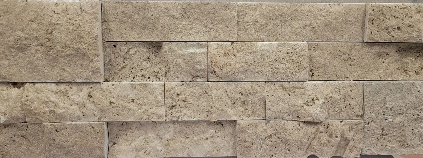 Tan stacked stone wall with beige and tan rectangular blocks and visible mortar lines