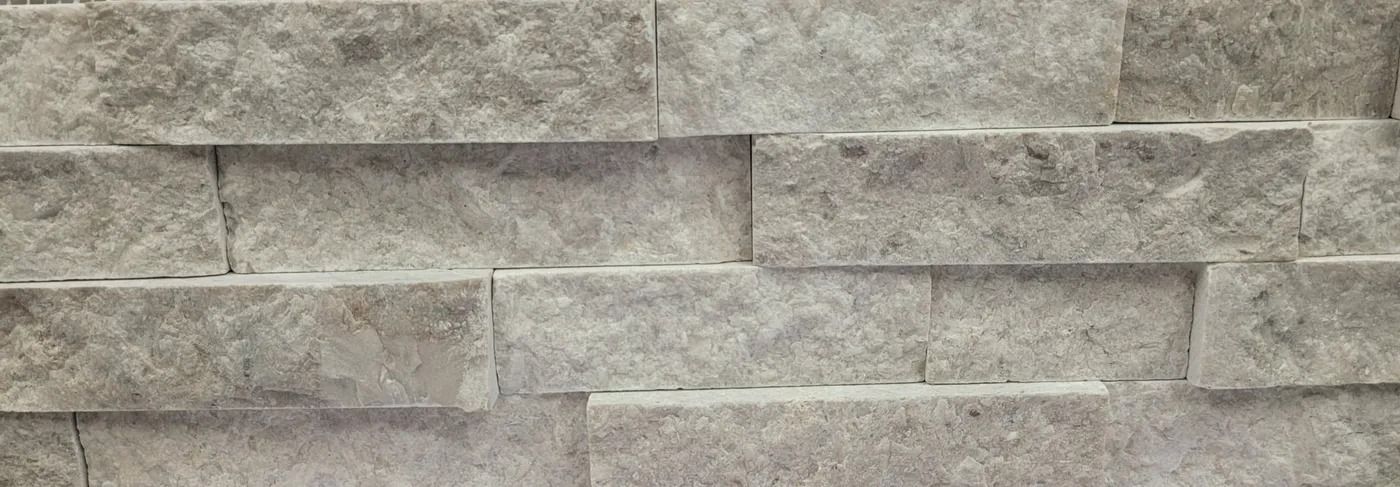 Gray stacked stone wall with rough, rectangular blocks and horizontal seams