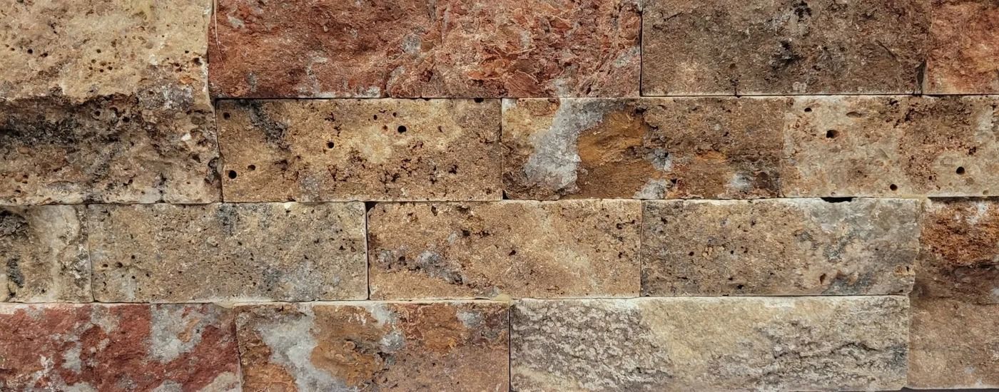 Close-up of a tan and red brick wall with textured, weathered stones.