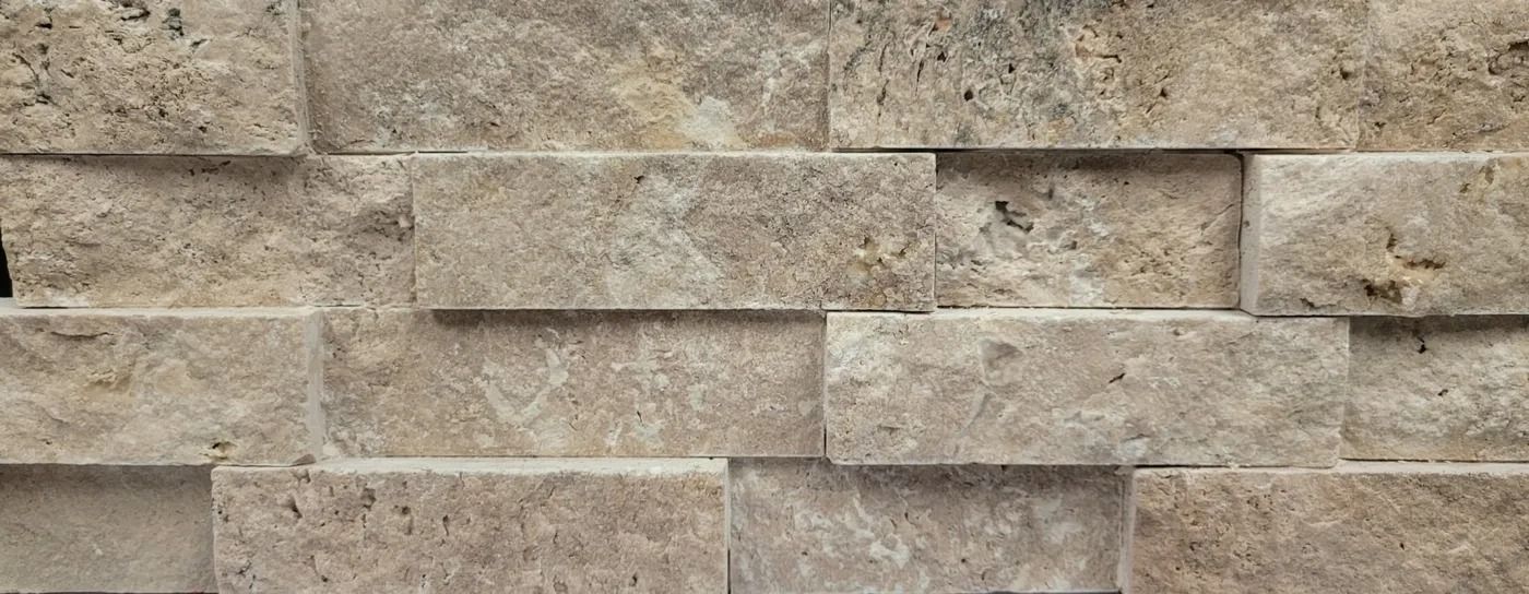 Beige stacked stone wall with horizontal rectangular blocks and textured surface