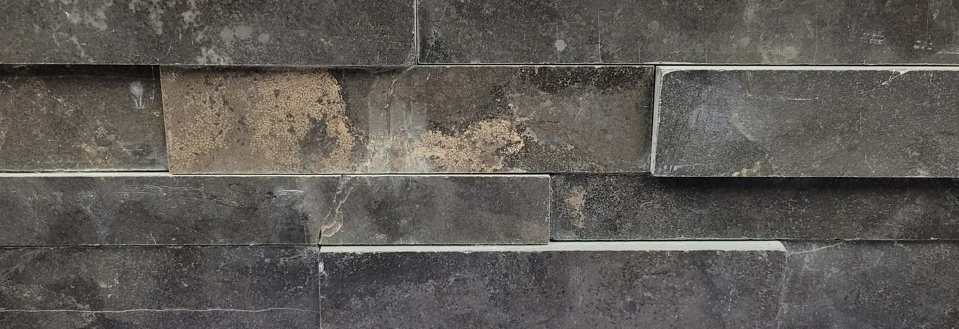 Close-up of a weathered gray stone wall with stacked rectangular blocks and mortar lines.