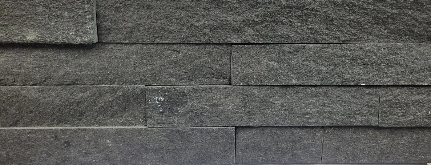 Dark gray stone brick wall with staggered rectangular blocks