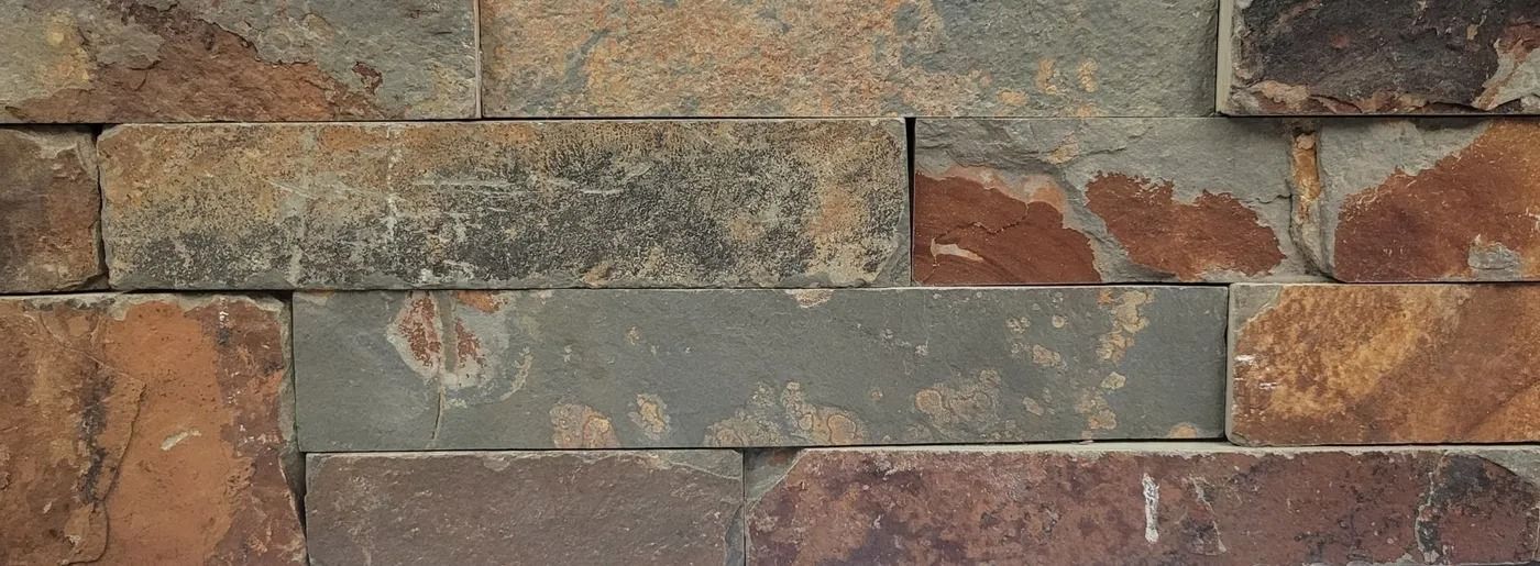 Weathered stone wall with multicolored rectangular masonry blocks and chipped plaster patches