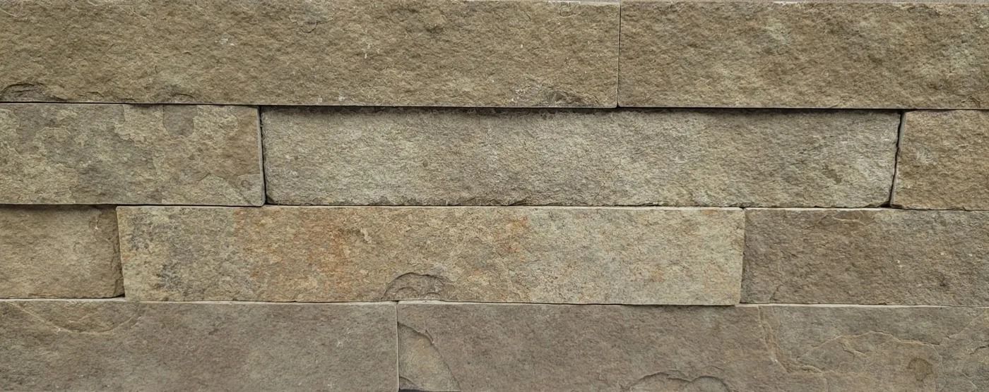 Stacked beige stone wall with horizontal rectangular blocks and visible mortar lines