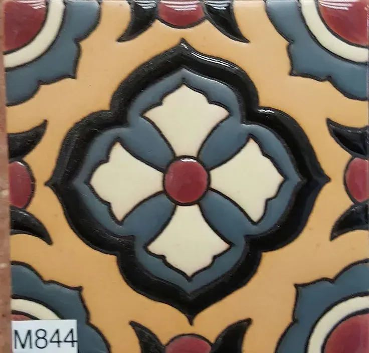Decorative ceramic tile with a blue, black, cream, and red floral geometric pattern