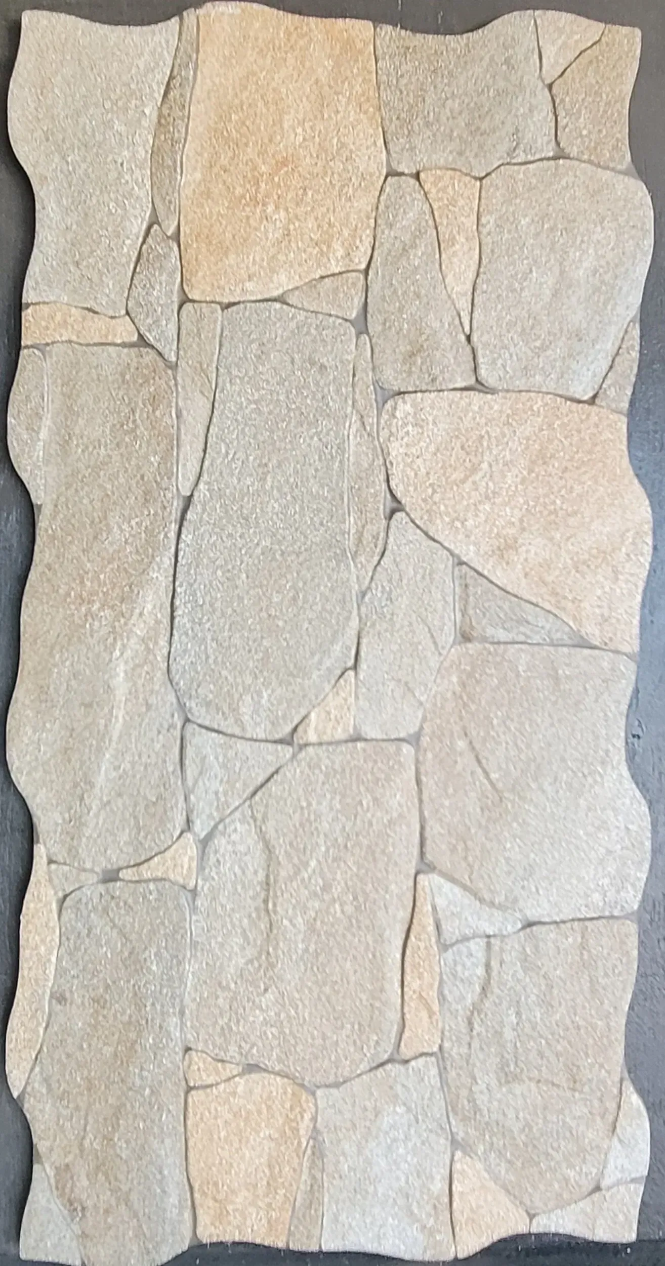 Vertical panel of light tan and gray irregular stone tiles on a dark background