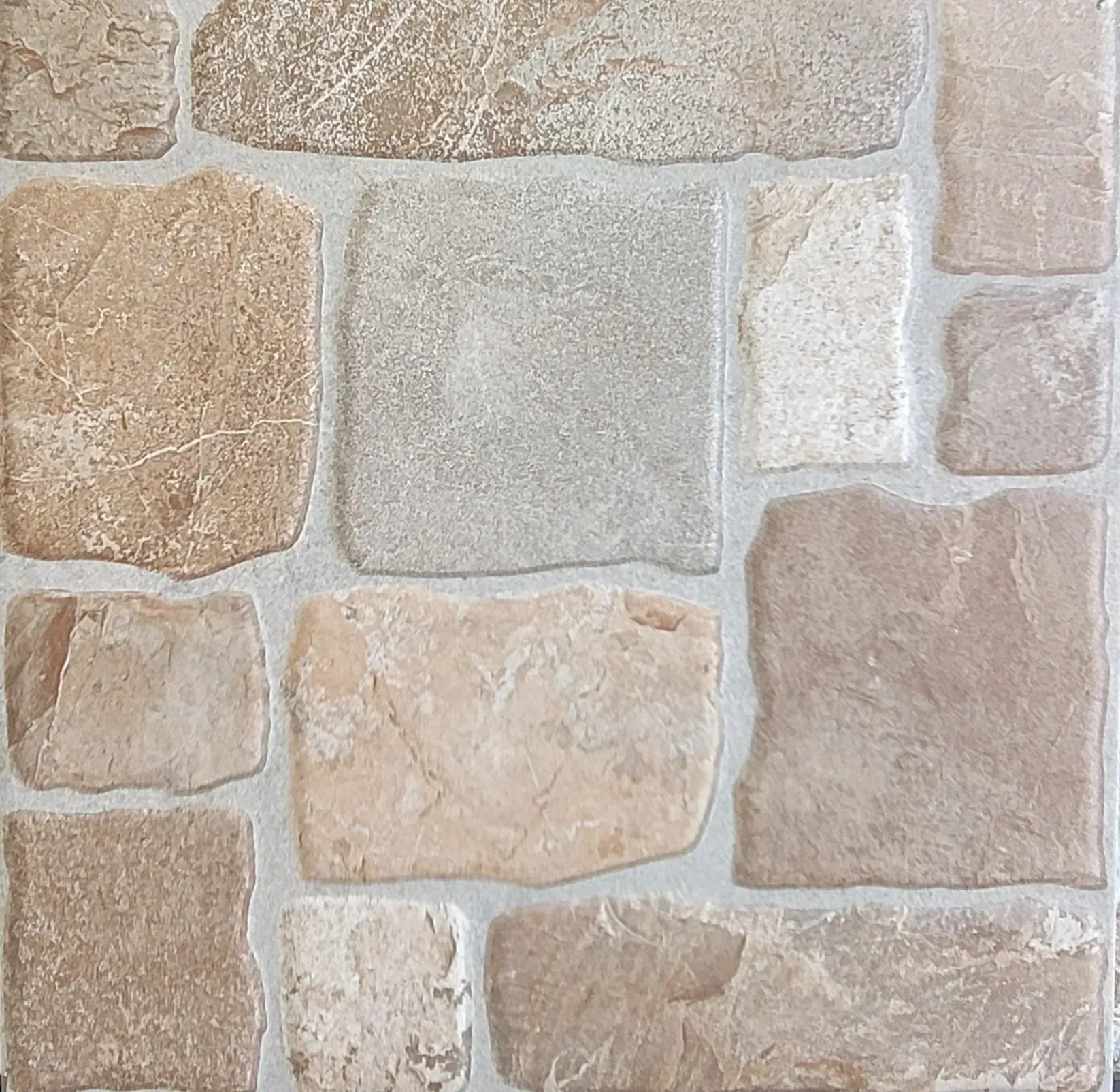 Close-up of a tan and gray stone wall with irregular rectangular stones and mortar joints