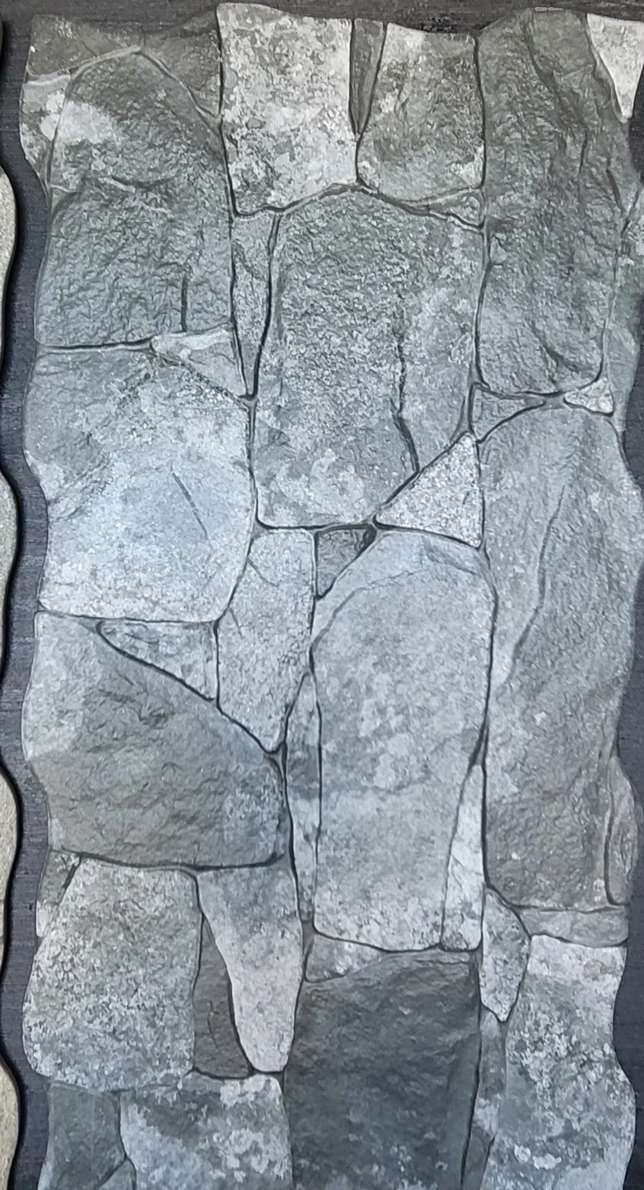 Close-up of a gray stone wall with irregularly shaped rocks and mortar lines