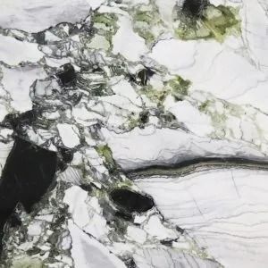 White marble-like stone with gray veining and green mineral patches, plus a dark black crack on the left.
