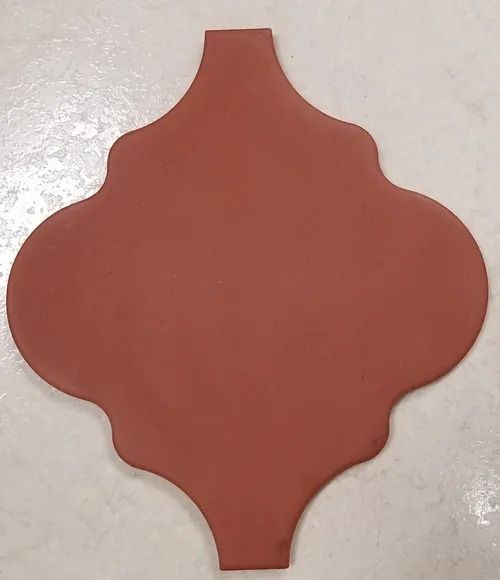 Terracotta-colored decorative tile with scalloped edges and narrow tabs at top and bottom