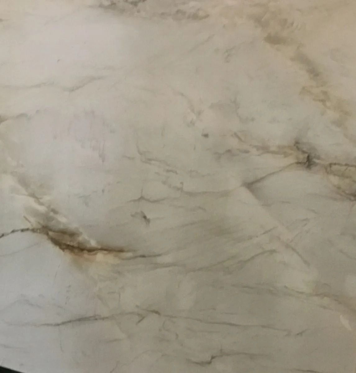 Close-up of a beige marble surface with subtle gray veining and brown streaks