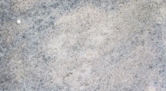 Close-up of a light gray, speckled stone or concrete surface.