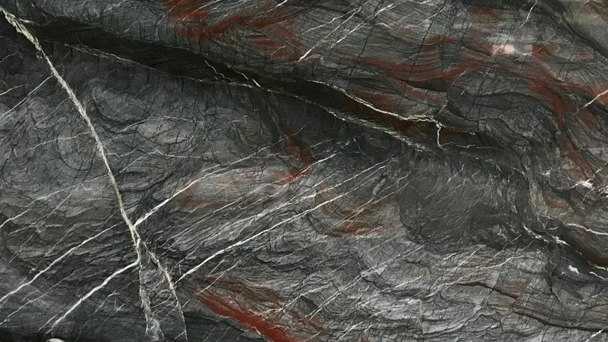 Dark gray marble-like stone texture with white and reddish veining.