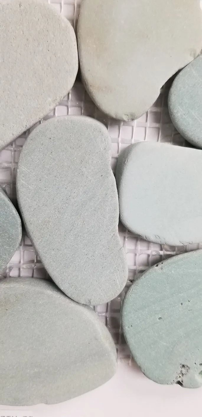 Pastel oval decorative stones arranged in a grid on a textured surface
