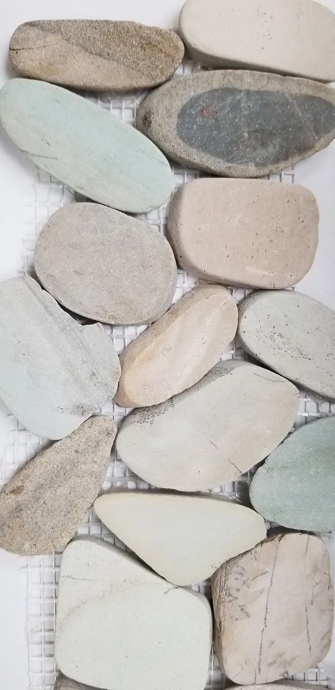Stacked smooth pebbles in white, beige, and gray tones forming a decorative stone wall pattern