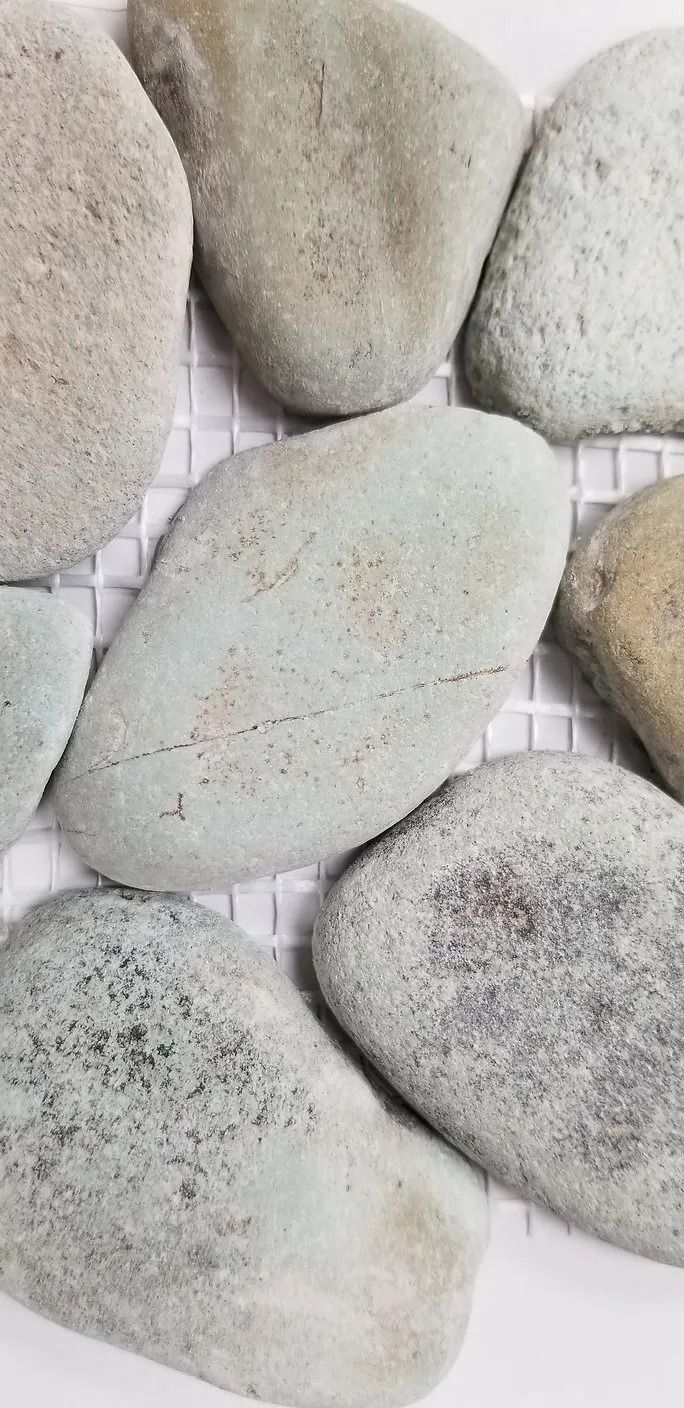 Close-up of smooth pale pebbles arranged on a white mesh surface