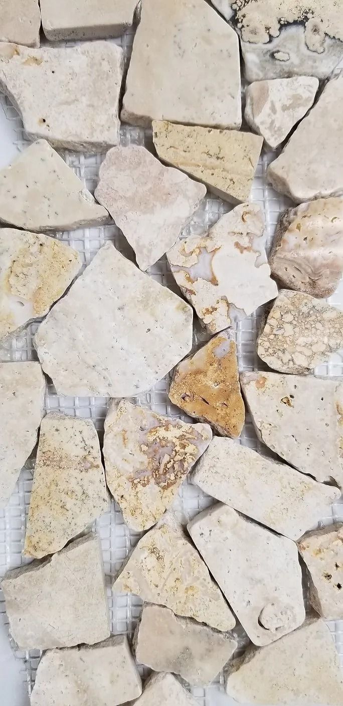 Close-up of irregular pale stone tiles with a few tan and beige pieces forming a mosaic pattern