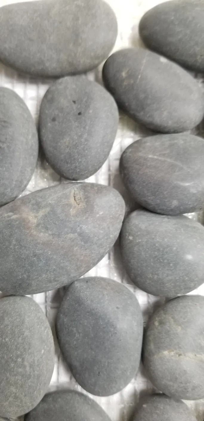 Smooth gray pebbles stacked closely together, filling the frame.