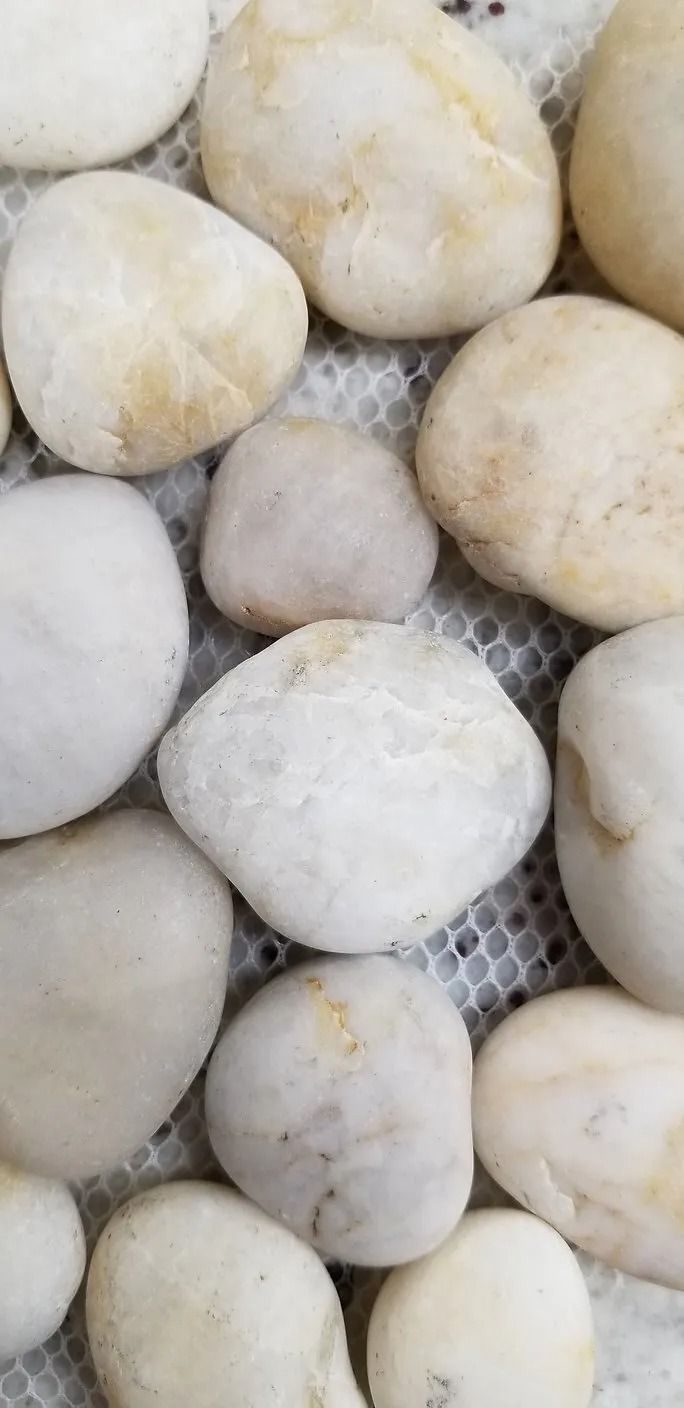 Close-up of pale round stones or dough balls on a mesh surface.